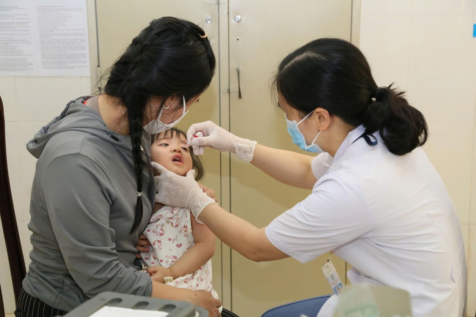 Trẻ được cán bộ y tế tại điểm tiêm Tân Lợi cho uống vắc xin OPV phòng bệnh bại liệt.